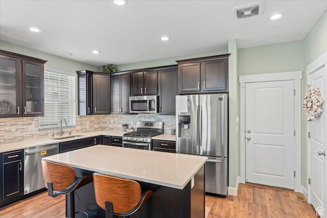 5131 W Mellow Way S, South Jordan, UT 84009 - kitchen featuring appliances with stainless steel finishes, backsplash, light countertops, light wood-type flooring, and a kitchen island