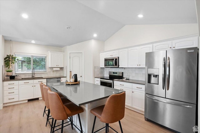 656 W 1310 N, Lehi, UT 84043 - kitchen with appliances with stainless steel finishes, a breakfast bar, dark countertops, light wood-style floors, and lofted ceiling