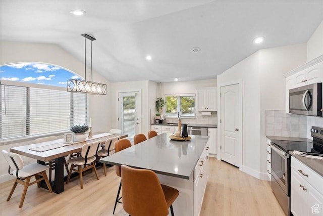 656 W 1310 N, Lehi, UT 84043 - kitchen featuring appliances with stainless steel finishes, light wood-type flooring, decorative backsplash, white cabinets, and a kitchen breakfast bar