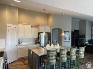 4613 W Brookport Cir S Unit V3-8, Herriman, UT 84096 - kitchen with freestanding refrigerator, a towering ceiling, light countertops, dark wood-style flooring, and a kitchen island with sink