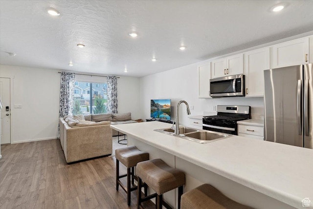 1826 N Blue Iris Ave, Tooele, UT 84074 - kitchen featuring stainless steel appliances, light wood finished floors, a kitchen breakfast bar, white cabinets, and recessed lighting