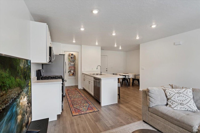 1826 N Blue Iris Ave, Tooele, UT 84074 - kitchen featuring appliances with stainless steel finishes, a breakfast bar area, wood finished floors, white cabinetry, and light countertops