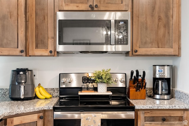 87 E Legacy Dr, Franklin, ID 83237 - kitchen featuring appliances with stainless steel finishes, brown cabinetry, and light stone countertops