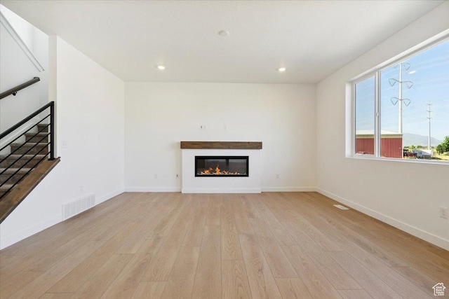 723 N Plainsman Dr Unit 109, Spanish Fork, UT 84660 - unfurnished living room featuring light wood-type flooring, a glass covered fireplace, stairs, and recessed lighting