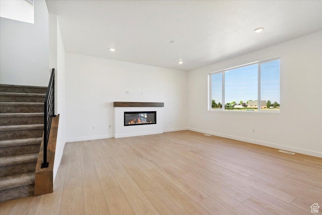 723 N Plainsman Dr Unit 109, Spanish Fork, UT 84660 - unfurnished living room featuring light wood-style flooring, stairs, a glass covered fireplace, and recessed lighting
