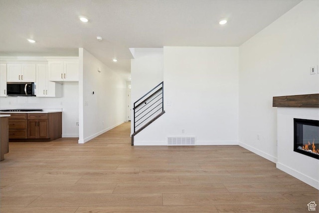 723 N Plainsman Dr Unit 109, Spanish Fork, UT 84660 - kitchen with stainless steel microwave, light wood-style floors, recessed lighting, cooktop, and white cabinets