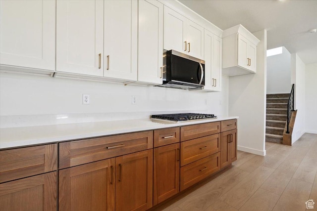 723 N Plainsman Dr Unit 109, Spanish Fork, UT 84660 - kitchen featuring appliances with stainless steel finishes, light wood finished floors, white cabinets, brown cabinets, and light countertops