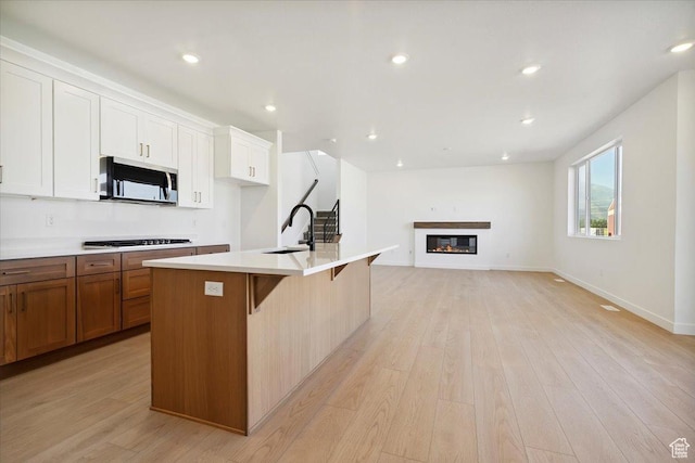 723 N Plainsman Dr Unit 109, Spanish Fork, UT 84660 - kitchen featuring stainless steel microwave, gas cooktop, a breakfast bar area, an island with sink, and light countertops