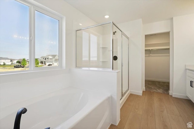 723 N Plainsman Dr Unit 109, Spanish Fork, UT 84660 - bathroom with a stall shower, wood finished floors, a garden tub, a spacious closet, and vanity