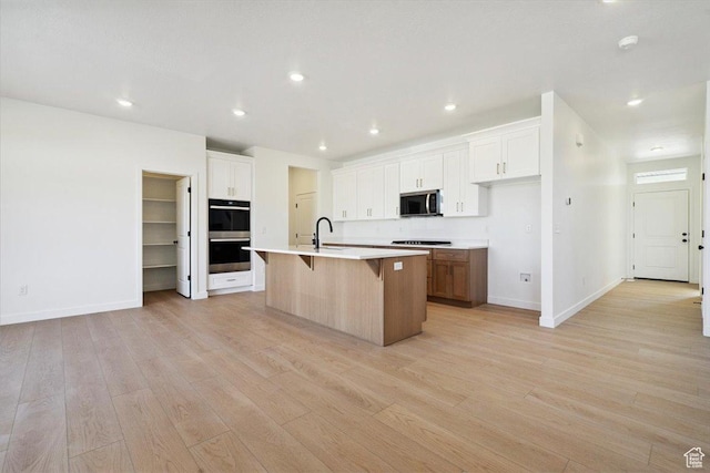 723 N Plainsman Dr Unit 109, Spanish Fork, UT 84660 - kitchen featuring appliances with stainless steel finishes, a kitchen breakfast bar, light wood-style flooring, an island with sink, and light countertops