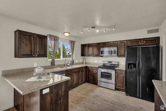 328 Pectol St, Washington, UT 84780 - kitchen with stainless steel appliances, dark brown cabinetry, a peninsula, light wood finished floors, and light stone countertops