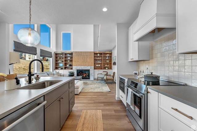 6957 W Farnsworth Peak Dr S Unit 314, West Jordan, UT 84081 - kitchen featuring appliances with stainless steel finishes, light wood-type flooring, decorative backsplash, a premium fireplace, and pendant lighting