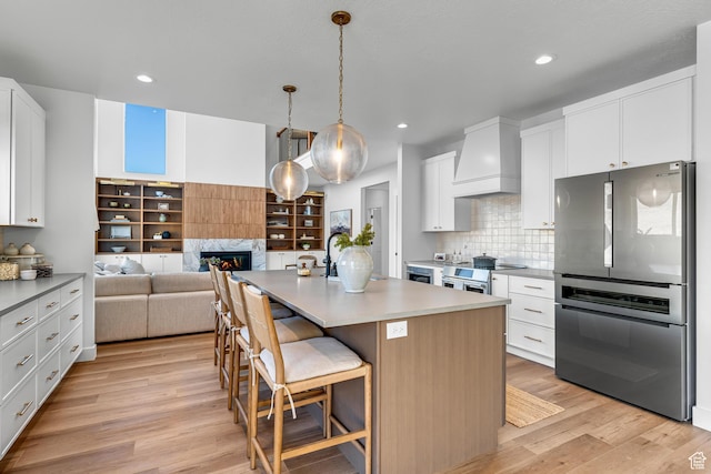 6957 W Farnsworth Peak Dr S Unit 314, West Jordan, UT 84081 - kitchen featuring freestanding refrigerator, custom exhaust hood, light wood-style floors, a glass covered fireplace, and a kitchen island