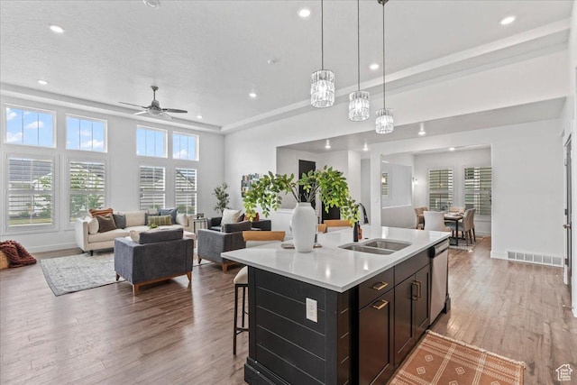 6153 W Poplar View Dr, South Jordan, UT 84009 - kitchen featuring light wood-type flooring, light countertops, open floor plan, stainless steel dishwasher, and a kitchen island with sink