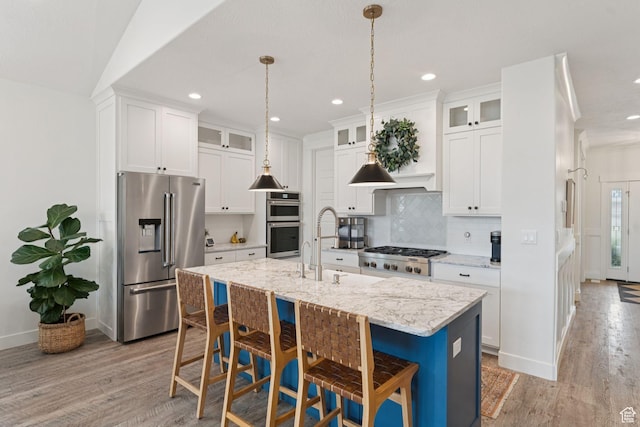 1968 W Silver Leaf Dr S, Mapleton, UT 84664 - kitchen with appliances with stainless steel finishes, light wood finished floors, a kitchen island with sink, a kitchen breakfast bar, and backsplash