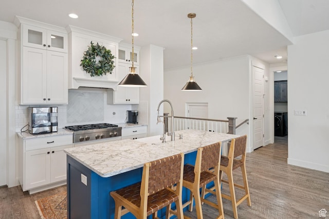 1968 W Silver Leaf Dr S, Mapleton, UT 84664 - kitchen with washer / dryer, light wood-style floors, stainless steel gas stovetop, decorative backsplash, and a kitchen bar