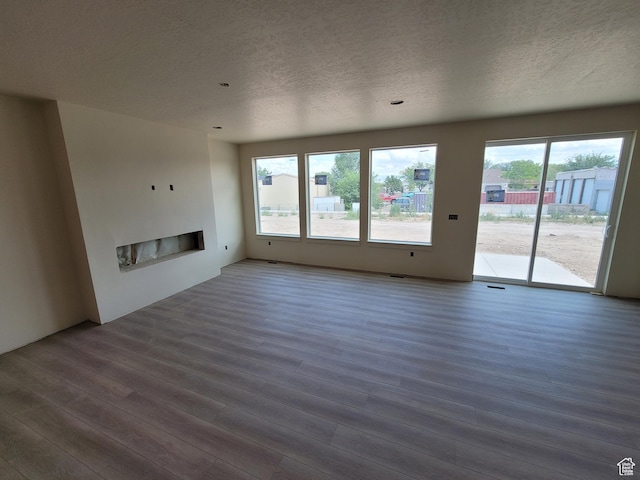 2909 S Richards View Rd Unit 6, Magna, UT 84044 - unfurnished living room featuring a textured ceiling, wood finished floors, and a glass covered fireplace