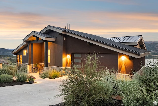 11411 N White Tail Ct, Hideout, UT 84036 - property exterior at dusk with concrete driveway, an attached garage, a standing seam roof, a metal roof, and stone siding