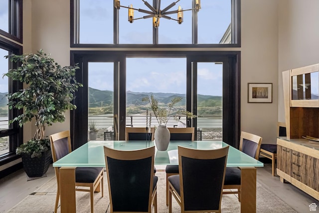 11411 N White Tail Ct, Hideout, UT 84036 - dining space with healthy amount of natural light, a chandelier, a towering ceiling, a mountain view, and wood finished floors
