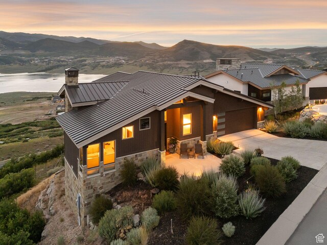 11411 N White Tail Ct, Hideout, UT 84036 - view of front of house with a standing seam roof, stone siding, a chimney, a metal roof, and concrete driveway