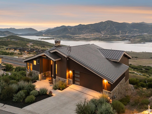 11411 N White Tail Ct, Hideout, UT 84036 - view of front of house featuring a standing seam roof, stone siding, a metal roof, a chimney, and a water and mountain view