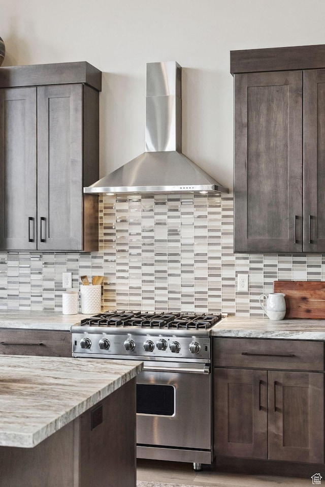 11411 N White Tail Ct, Hideout, UT 84036 - kitchen featuring wall chimney exhaust hood, high end stainless steel range, dark brown cabinets, and backsplash