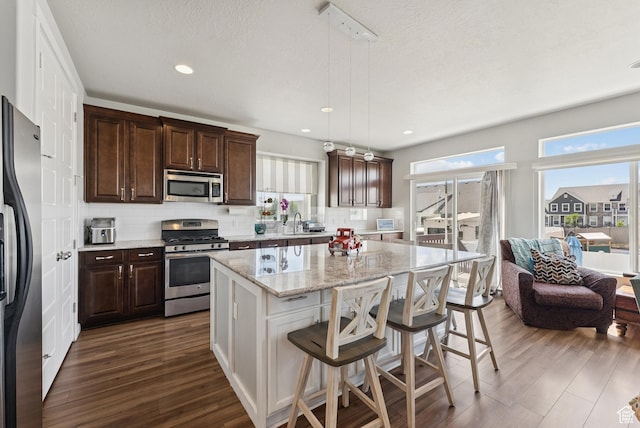 979 N Cold Creek Way, Layton, UT 84041 - kitchen with stainless steel appliances, dark wood-style flooring, a kitchen island, tasteful backsplash, and dark brown cabinets