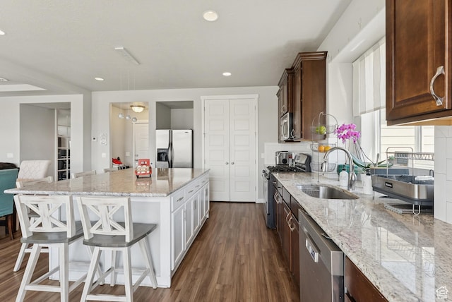 979 N Cold Creek Way, Layton, UT 84041 - kitchen featuring appliances with stainless steel finishes, light stone counters, dark wood-style floors, a breakfast bar area, and a center island