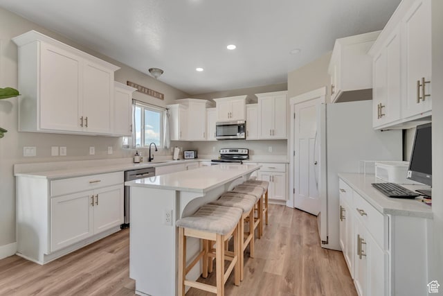 342 W Royal Land Dr, Santaquin, UT 84655 - kitchen featuring appliances with stainless steel finishes, light wood-style floors, white cabinetry, a breakfast bar area, and recessed lighting