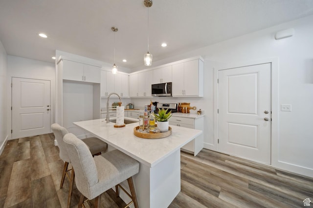 762 E Gables St S Unit 101, Midvale, UT 84047 - kitchen featuring stainless steel microwave, white cabinets, a breakfast bar, light countertops, and wood finished floors