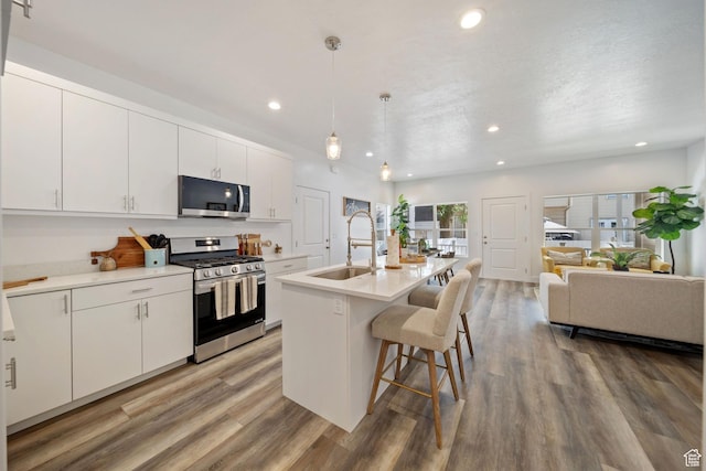 762 E Gables St S Unit 101, Midvale, UT 84047 - kitchen with appliances with stainless steel finishes, open floor plan, a kitchen bar, recessed lighting, and light wood-style floors
