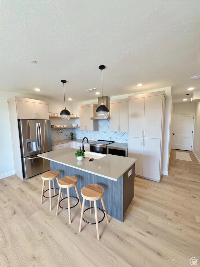 70 E Hwy 153 Unit A4, Beaver, UT 84713 - kitchen with stainless steel appliances, wall chimney exhaust hood, light wood-style floors, backsplash, and a textured ceiling
