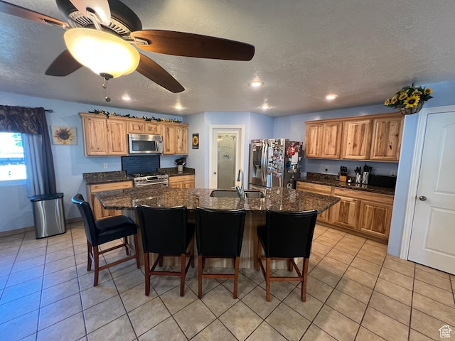 251 N 580 W, Monroe, UT 84754 - kitchen featuring stainless steel appliances, a kitchen breakfast bar, an island with sink, a textured ceiling, and light tile patterned floors