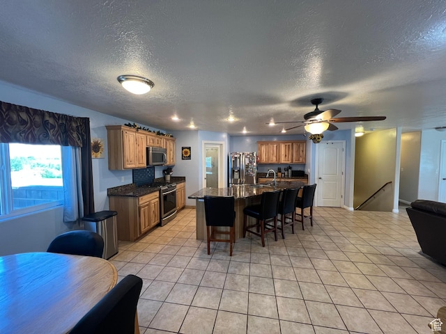 251 N 580 W, Monroe, UT 84754 - kitchen with stainless steel appliances, a textured ceiling, a kitchen breakfast bar, open floor plan, and a ceiling fan