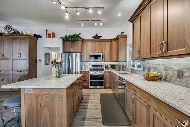 9078 S Harkness Dr W, West Jordan, UT 84088 - kitchen featuring stainless steel appliances, a center island, decorative backsplash, and light wood finished floors