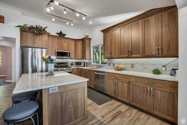 9078 S Harkness Dr W, West Jordan, UT 84088 - kitchen with appliances with stainless steel finishes, light wood finished floors, a kitchen breakfast bar, and backsplash