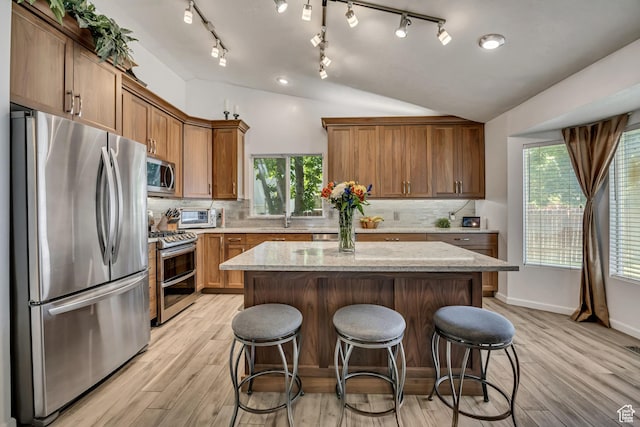 9078 S Harkness Dr W, West Jordan, UT 84088 - kitchen with stainless steel appliances, light wood-type flooring, a kitchen island, a kitchen breakfast bar, and lofted ceiling