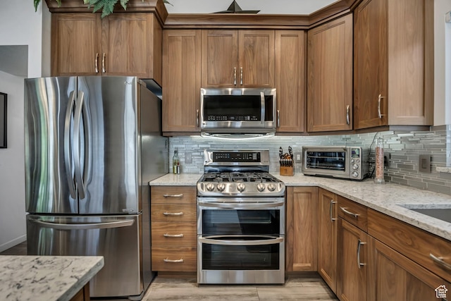 9078 S Harkness Dr W, West Jordan, UT 84088 - kitchen featuring stainless steel appliances, brown cabinetry, tasteful backsplash, and light stone counters