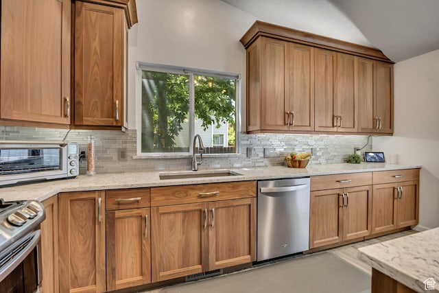 9078 S Harkness Dr W, West Jordan, UT 84088 - kitchen with appliances with stainless steel finishes, decorative backsplash, light stone countertops, vaulted ceiling, and brown cabinets