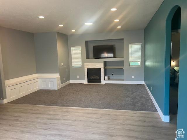 5298 W Icehouse Way, West Jordan, UT 84081 - unfurnished living room featuring carpet, recessed lighting, arched walkways, healthy amount of natural light, and wood finished floors