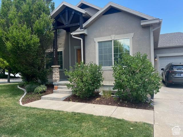 5298 W Icehouse Way, West Jordan, UT 84081 - view of front of house with stucco siding, a front lawn, an attached garage, and concrete driveway