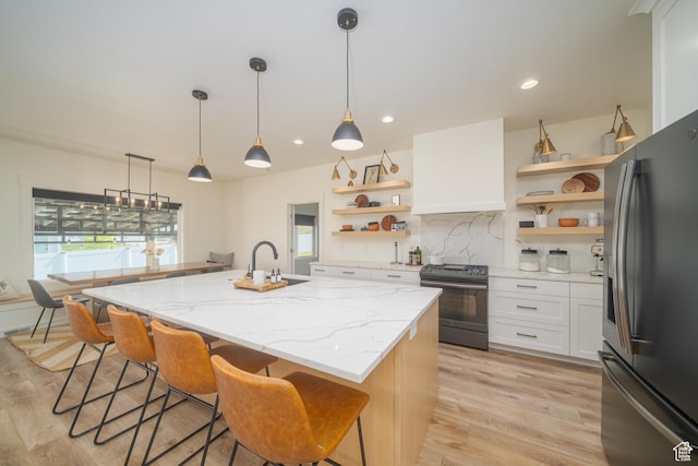 142 N 1100 E, Hyde Park, UT 84318 - kitchen with stainless steel appliances, open shelves, an island with sink, light wood-style floors, and custom exhaust hood