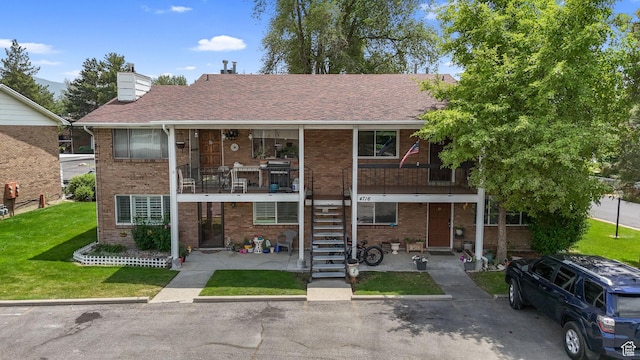 4716 S 700 E Unit 33, Murray, UT 84107 - view of property featuring a front lawn, brick siding, stairway, a chimney, and a shingled roof