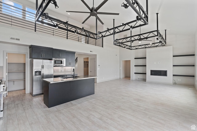 2628 E 40 N Unit 9, Spanish Fork, UT 84660 - kitchen with appliances with stainless steel finishes, a towering ceiling, light wood finished floors, dark cabinetry, and a kitchen island with sink