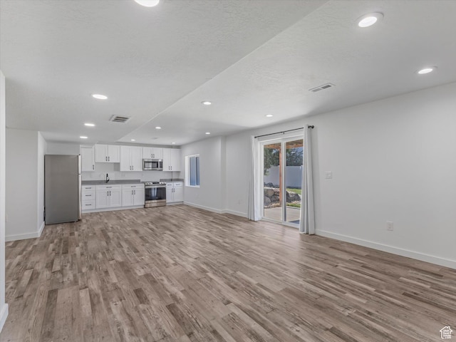 1907 E Brooklyn Cir N, Saratoga Springs, UT 84045 - unfurnished living room featuring light wood finished floors and recessed lighting