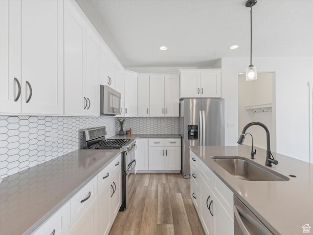 1907 E Brooklyn Cir N, Saratoga Springs, UT 84045 - kitchen with appliances with stainless steel finishes, light wood-type flooring, pendant lighting, white cabinets, and decorative backsplash
