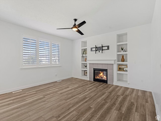 1907 E Brooklyn Cir N, Saratoga Springs, UT 84045 - unfurnished living room featuring wood finished floors, a ceiling fan, a tile fireplace, and built in features