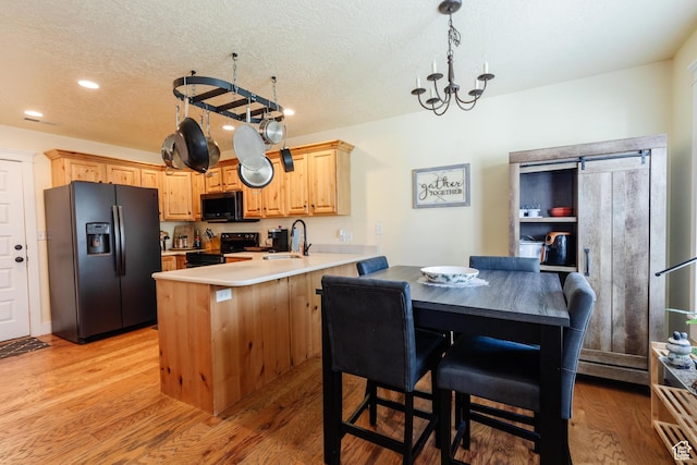 265 W 1010 S, Logan, UT 84321 - kitchen featuring black appliances, a peninsula, light wood-style flooring, a textured ceiling, and light countertops