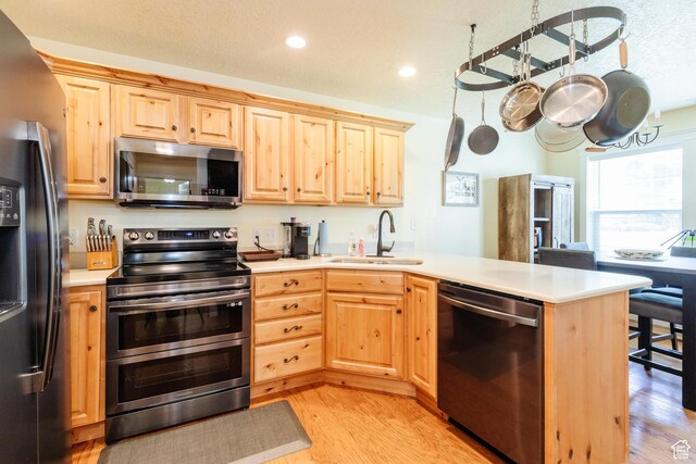 265 W 1010 S, Logan, UT 84321 - kitchen with appliances with stainless steel finishes, light brown cabinetry, a peninsula, light wood finished floors, and light countertops