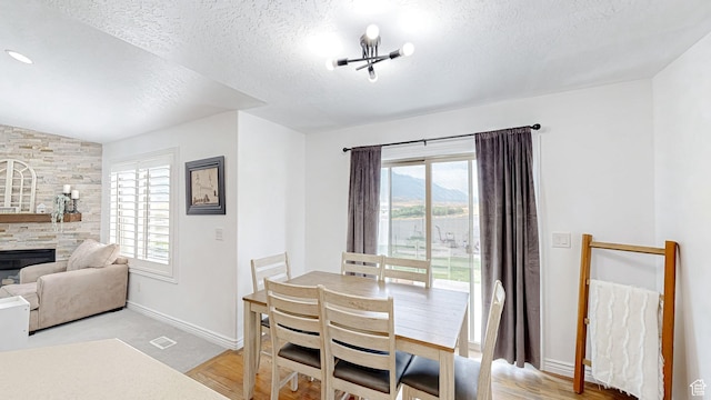 645 Stonebrook Ln, Santaquin, UT 84655 - dining area with a textured ceiling, plenty of natural light, lofted ceiling, and a stone fireplace